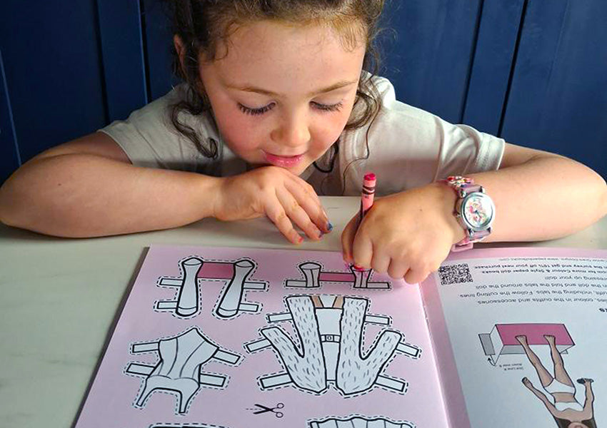 Child coloring a picture of a house with crayons at a table.